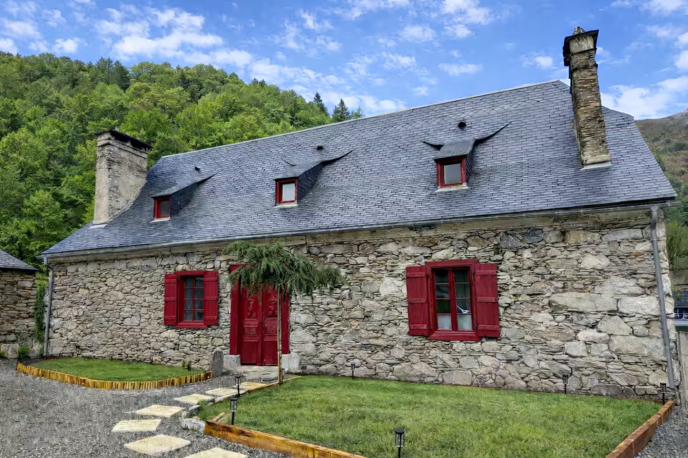Façade en pierre de L'Âtre de Pierre, volets rouges