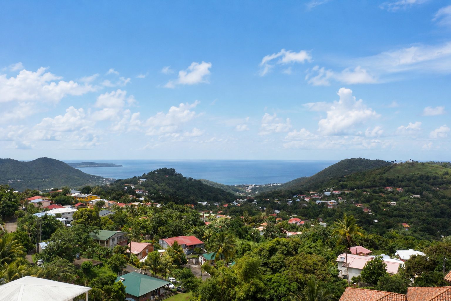 Panorama depuis les hauteurs de Sainte-Luce : collines, toits créoles et mer des Caraïbes